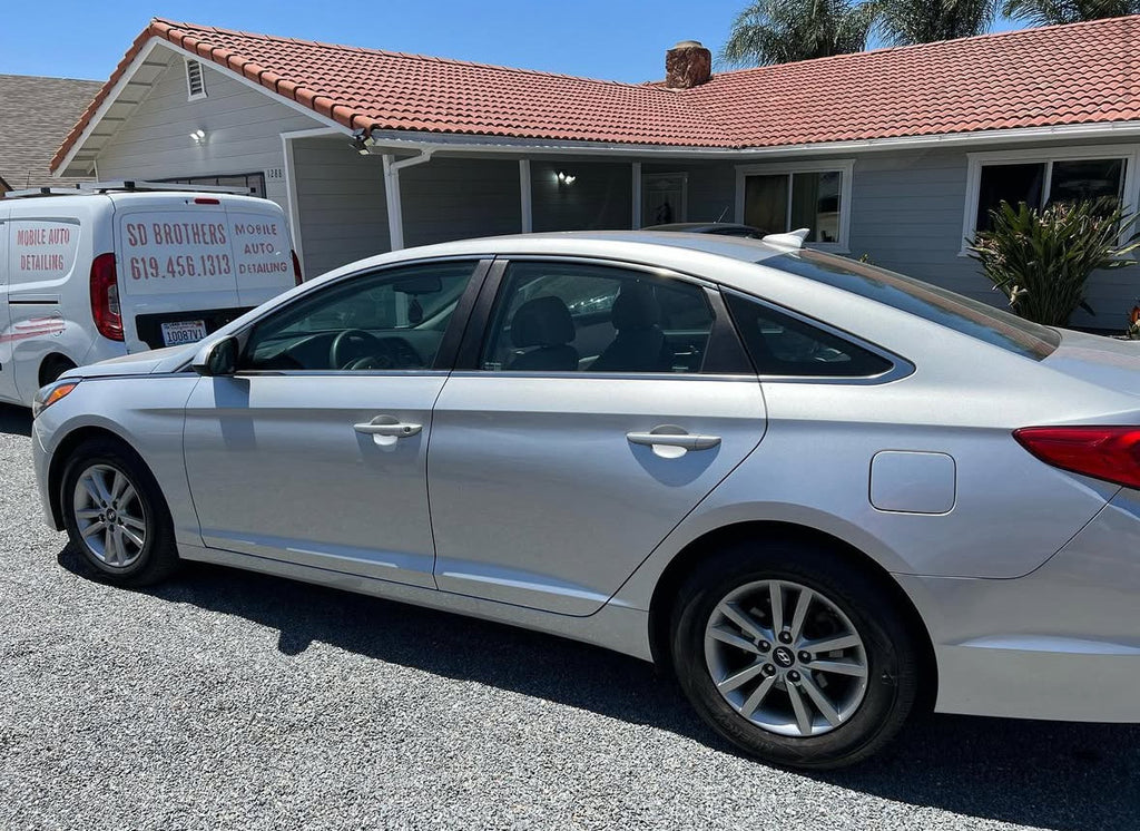 White car parked in front of a house with a clear sky.